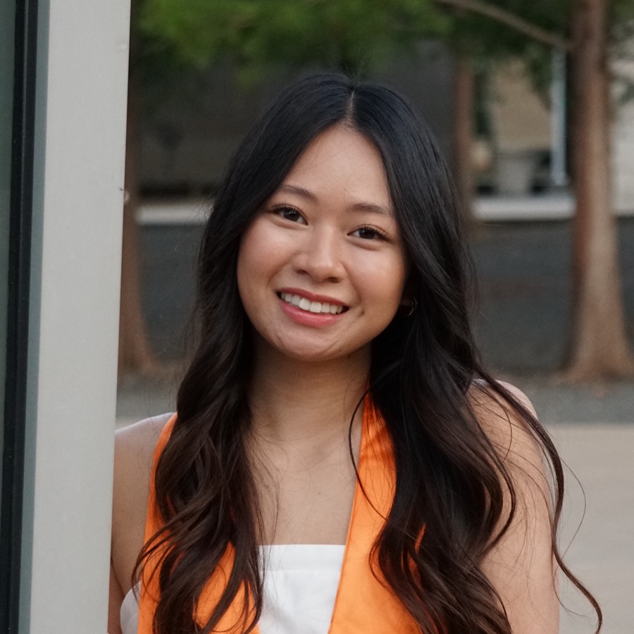 Laney smiling in a white dress and orange graduation stole